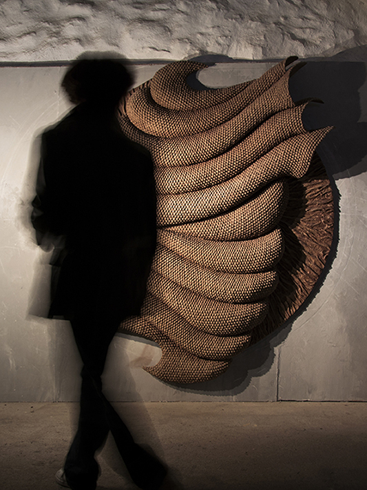 Large sculptural wall installation with textured material surfaces designed for architectural interior space creating spatial depth 